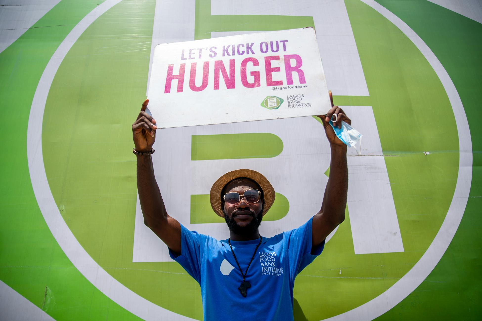Man holding a sign promoting a hunger awareness campaign at an outdoor event.