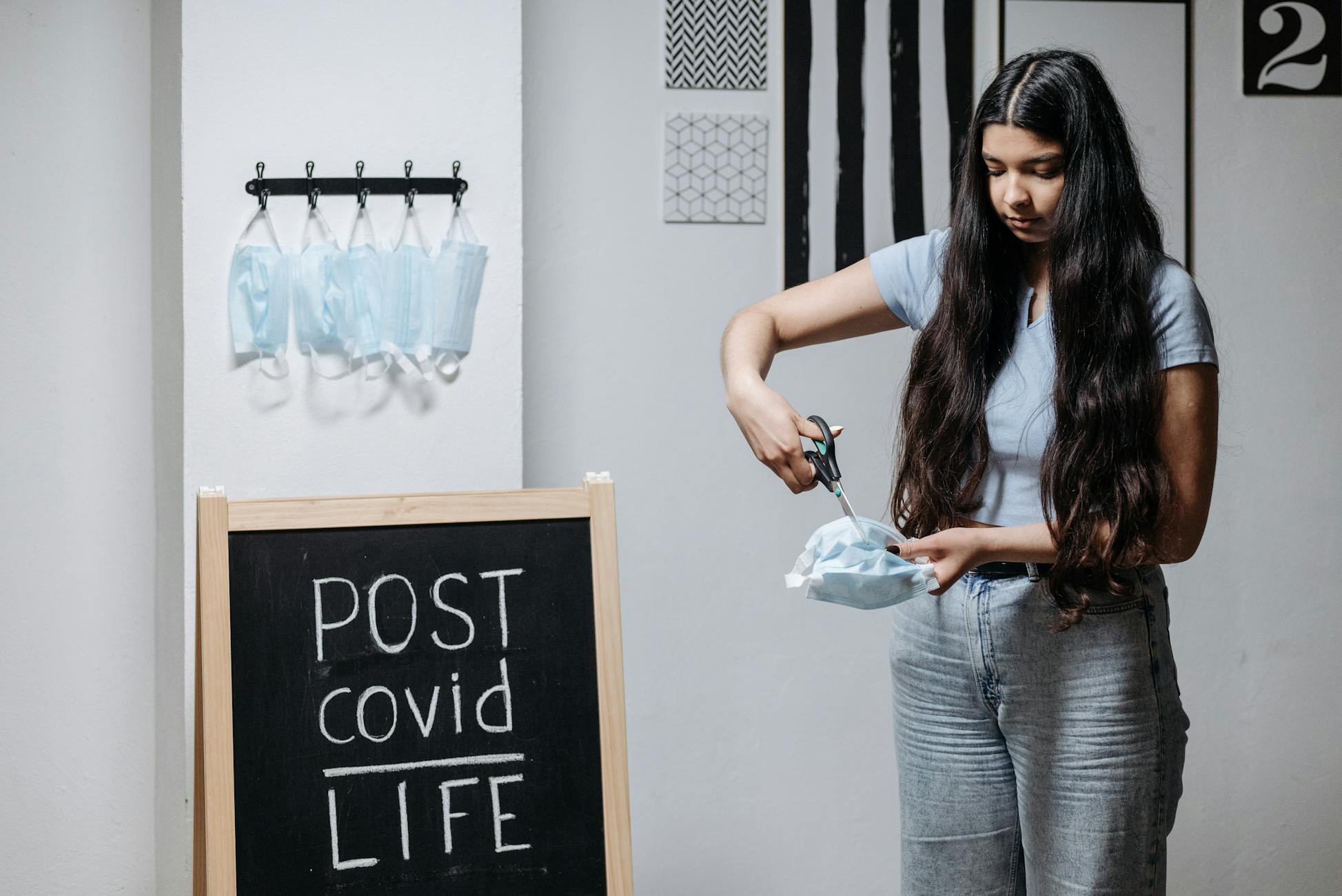 A young woman symbolically cuts a face mask in a post-COVID life setting.
